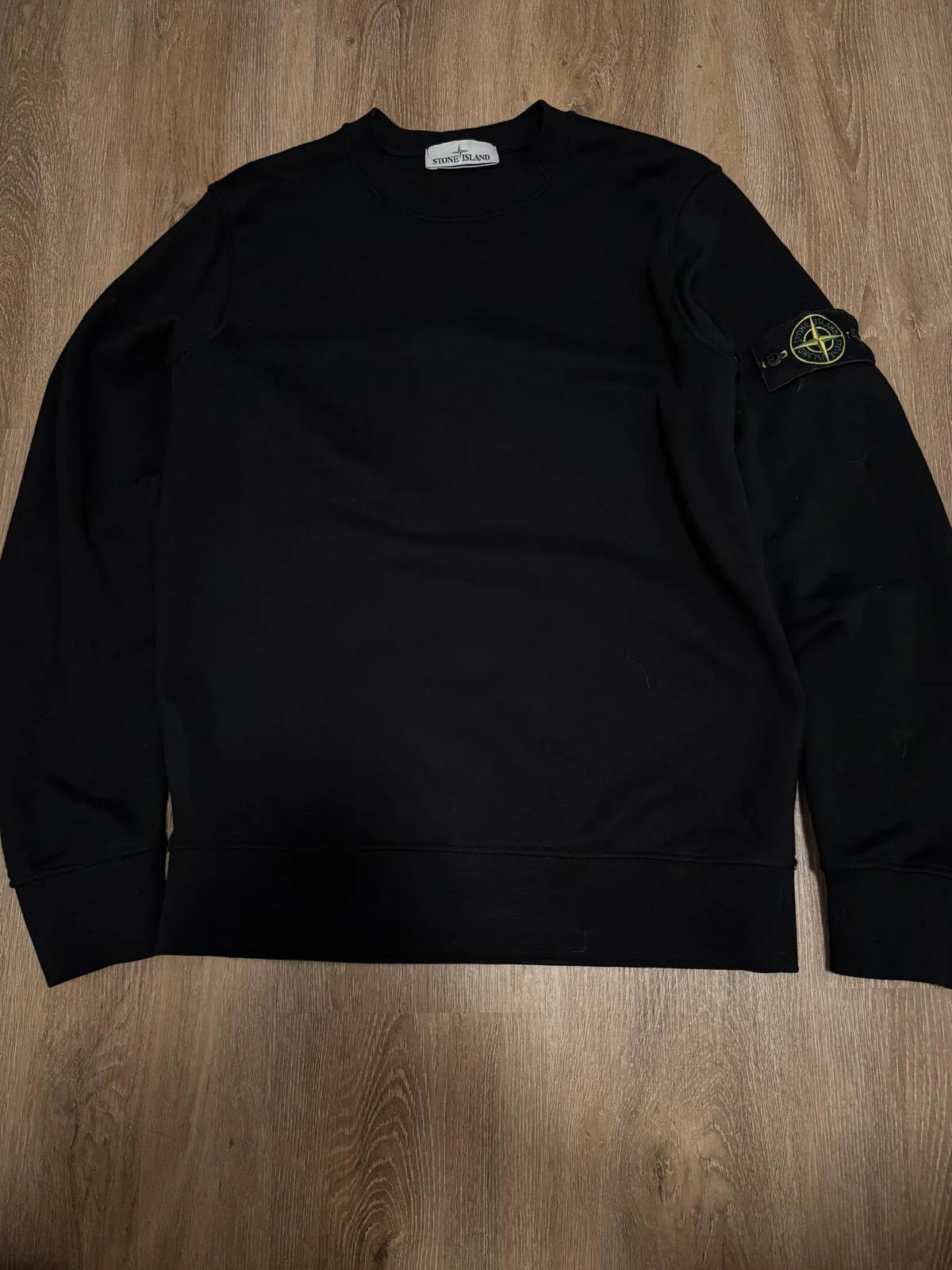Pull noir à col rond avec badge sur la manche.