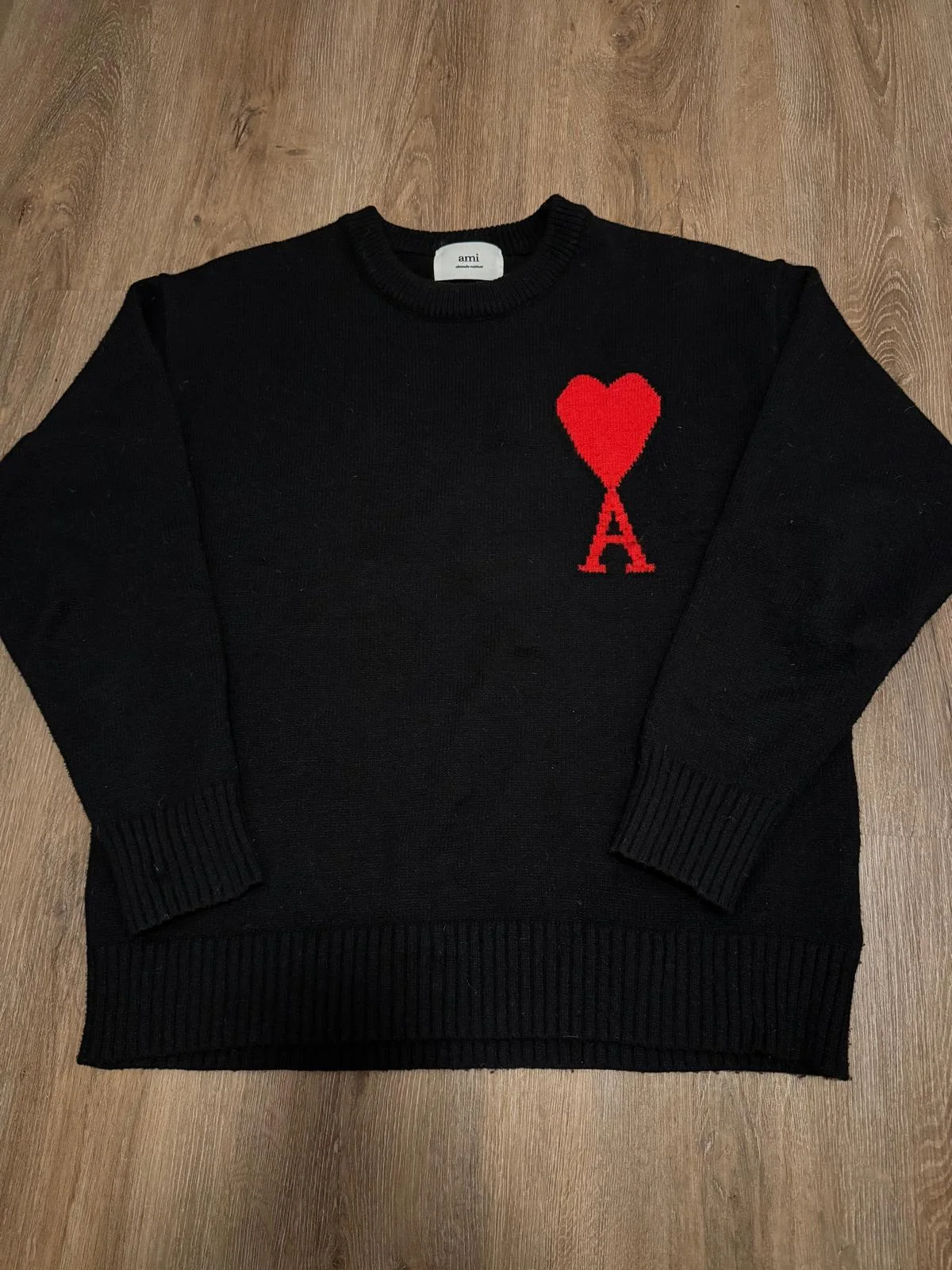 Pull en maille noire avec motif rouge sur la poitrine.